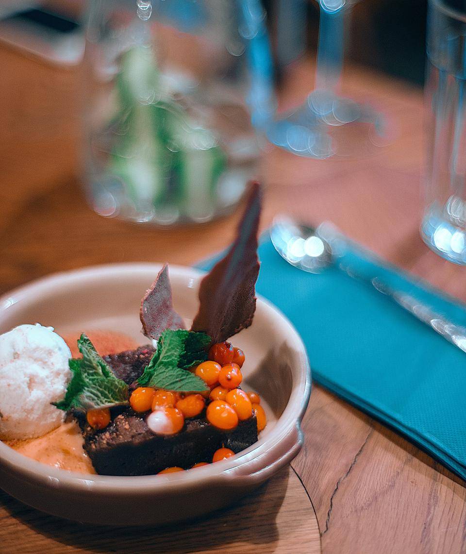 torta de chocolate dentro de prato rodeado de frutas em cima de mesa de madeira
